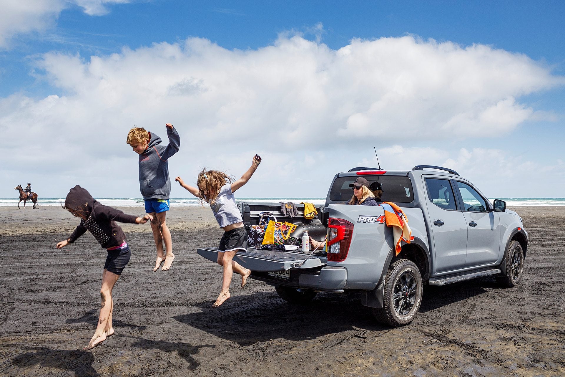 Kids jumping off back of Nissan Navara at Muriwai Beach