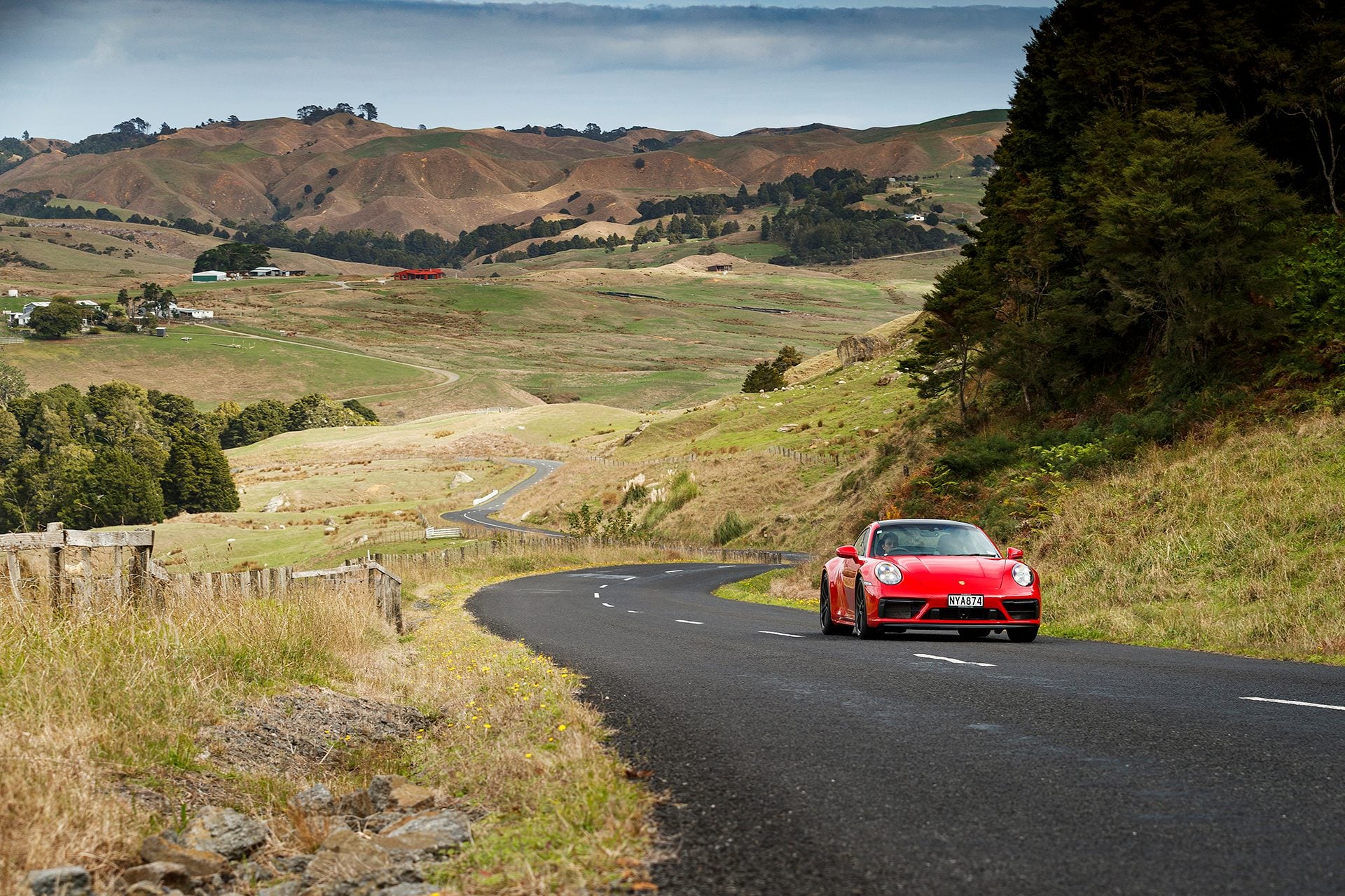 red Porsche 911 GTS driving through hills