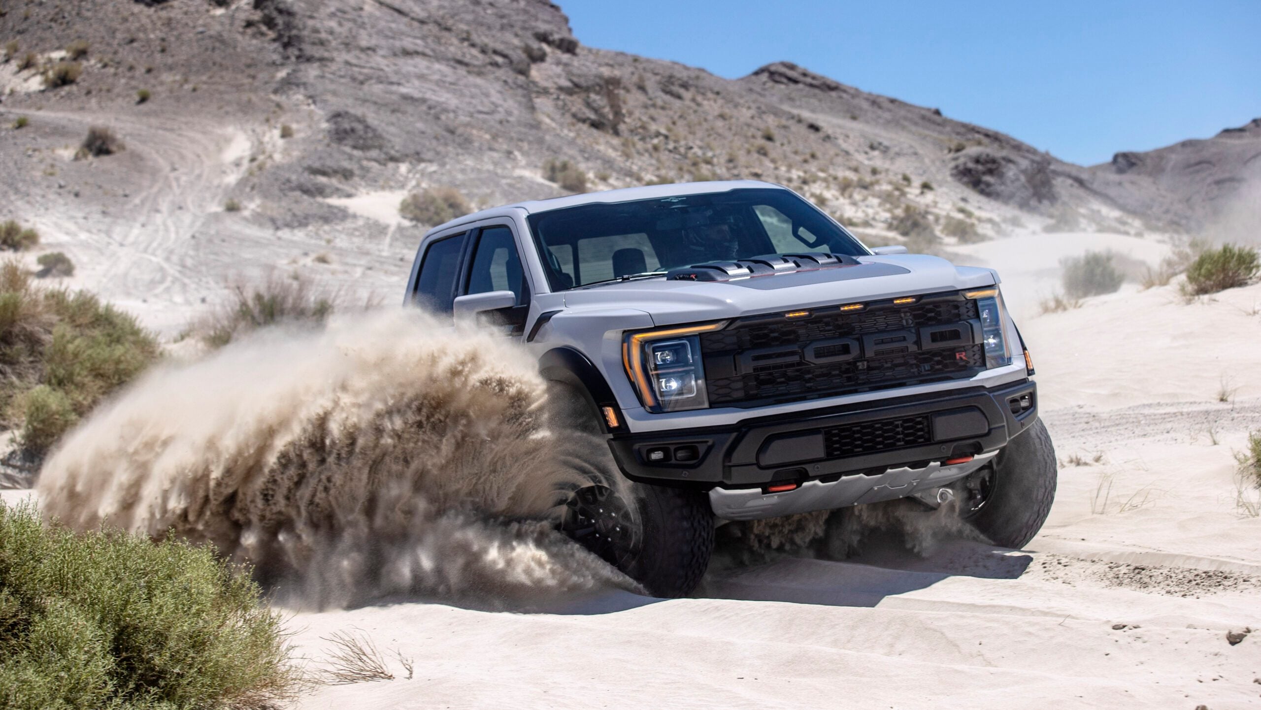 Ford F-150 Raptor R driving through sand in desert front three quarters