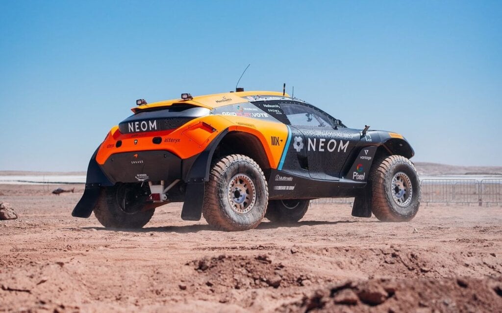 Extreme E race car rear three quarter view on dirt
