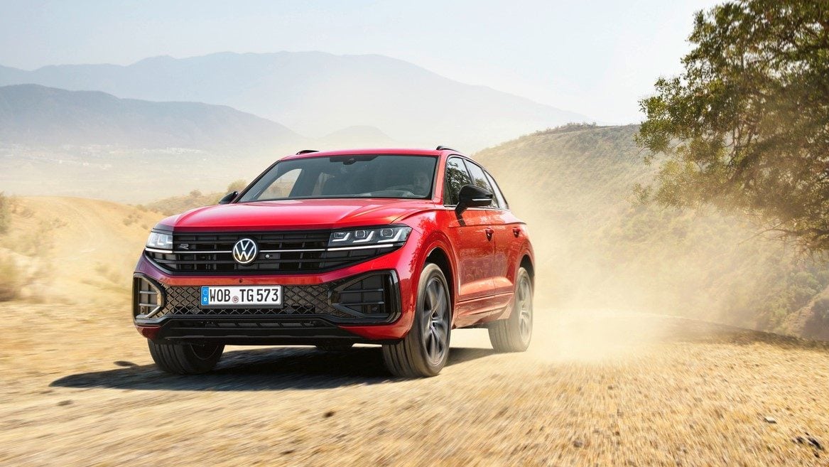 Third-generation Volkswagen Touareg driving on dirt past tree
