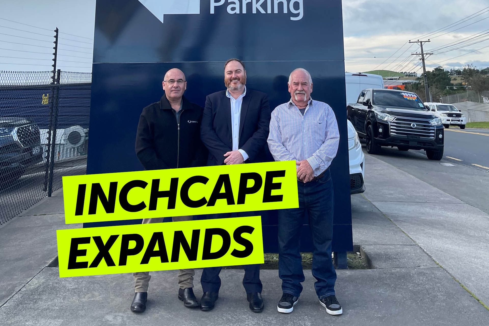 People standing by car dealership sign