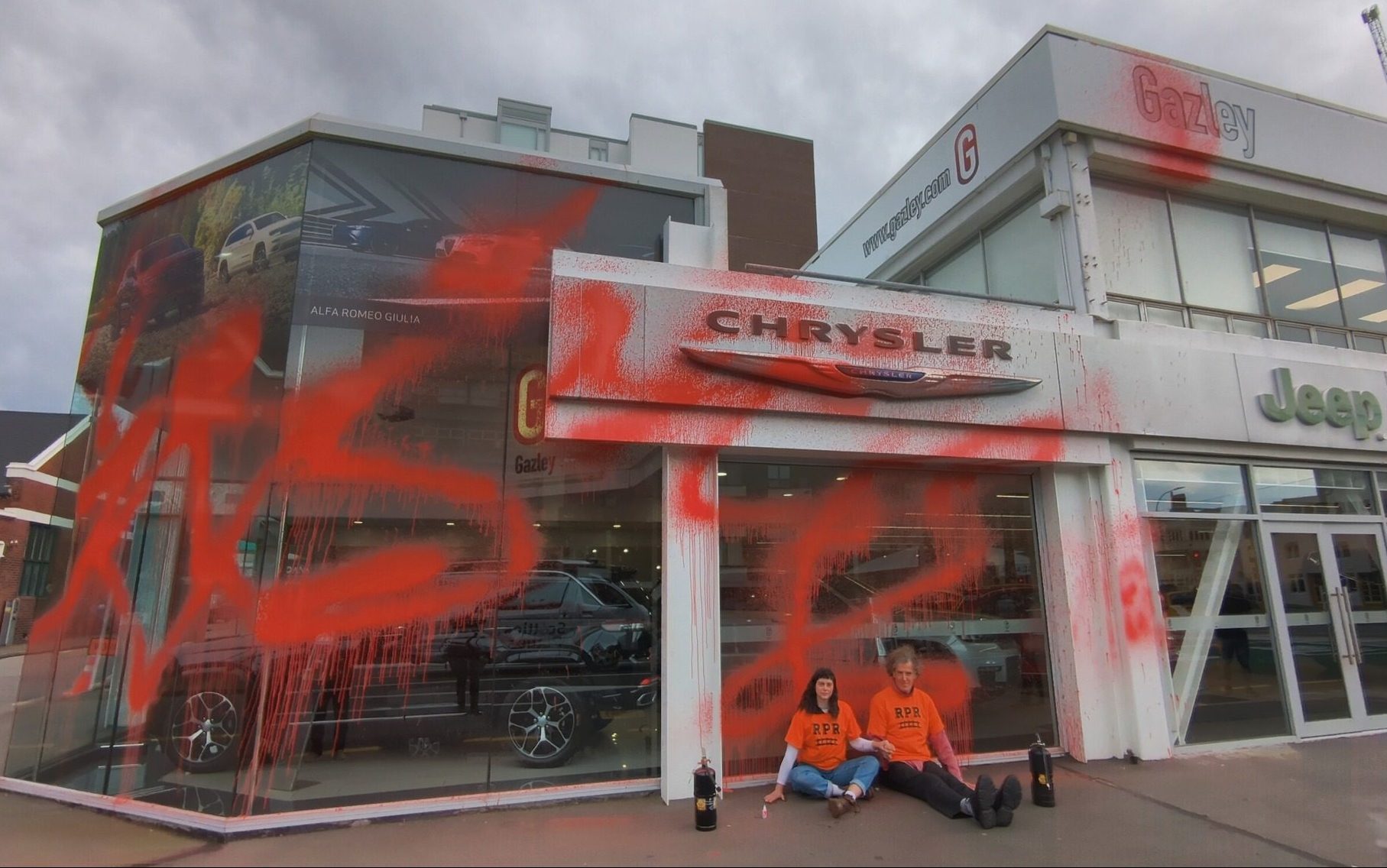 Climate activists sitting outside of vandalised luxury car dealership in Wellington
