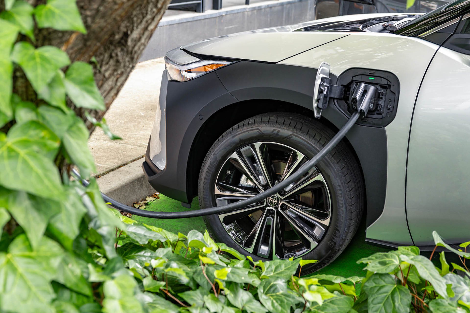 2024 Toyota bZ4X charging next to tree