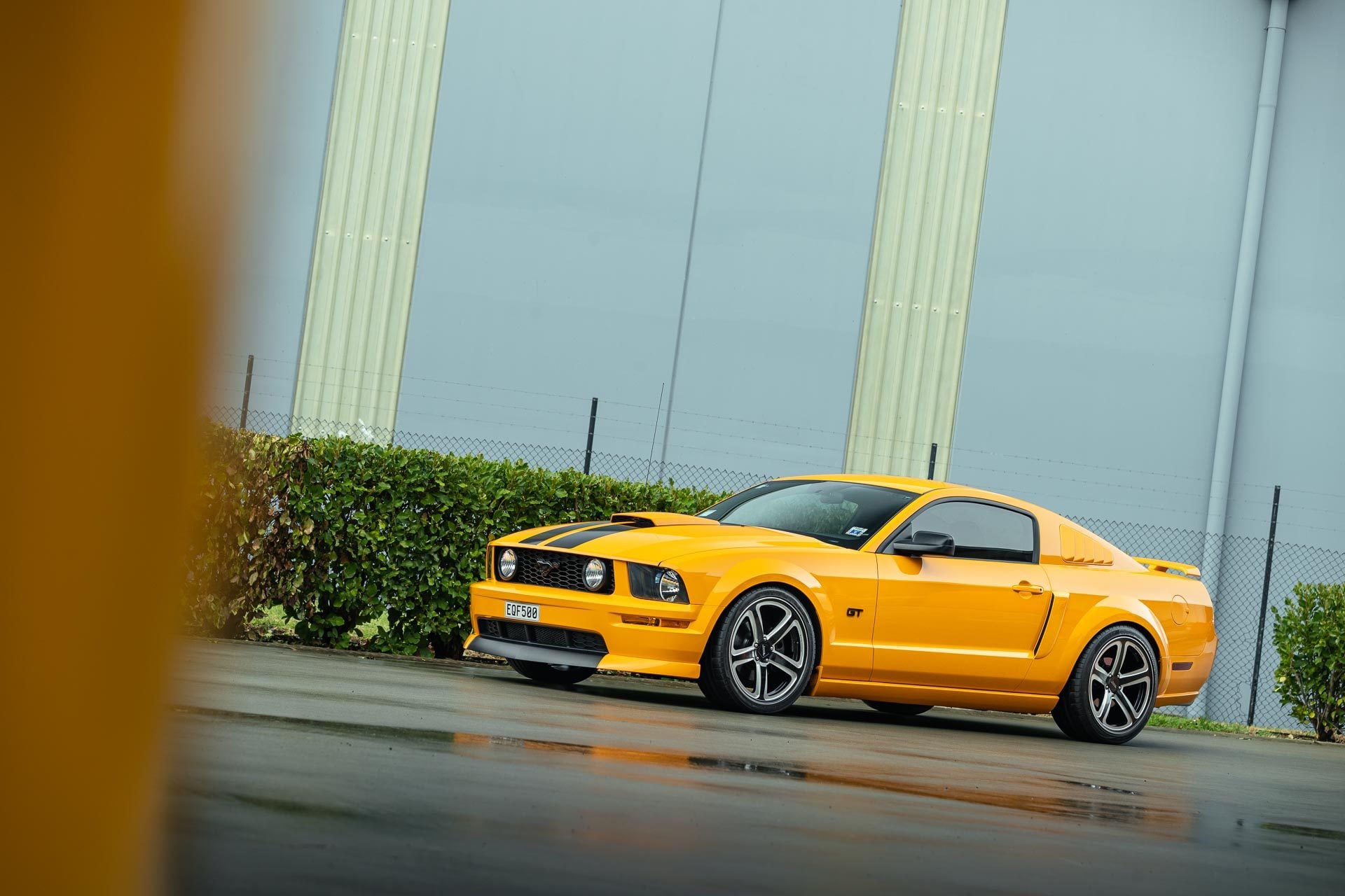 Ford Mustang GT 2007 in yellow, parked on a wet road
