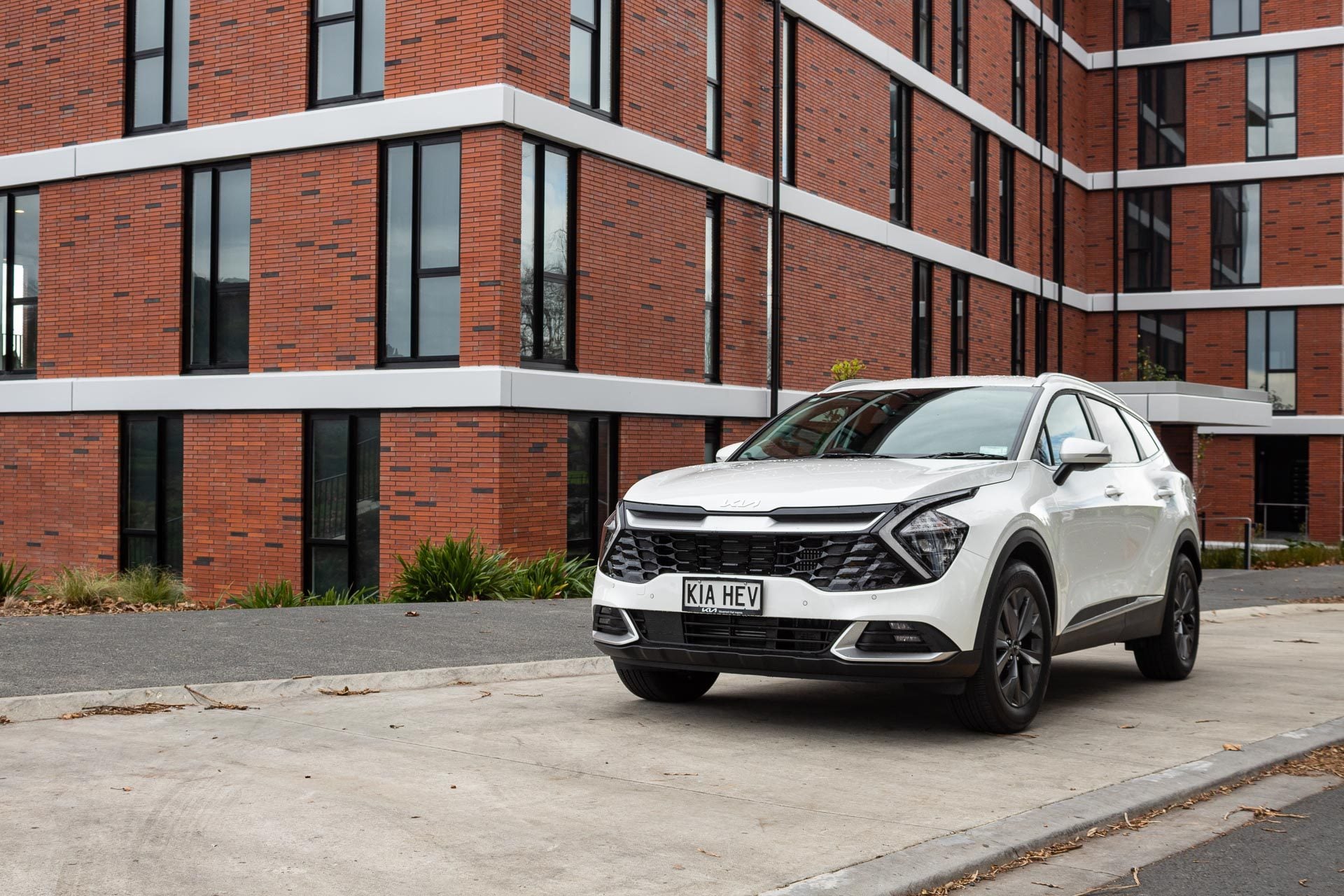 Kia Sportage front quarter angle, parked in front of a massive brick building