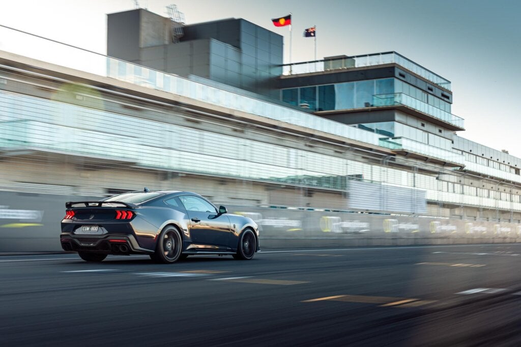 Ford Mustang Dark Horse in black, in a rolling shot taken on a racetrack