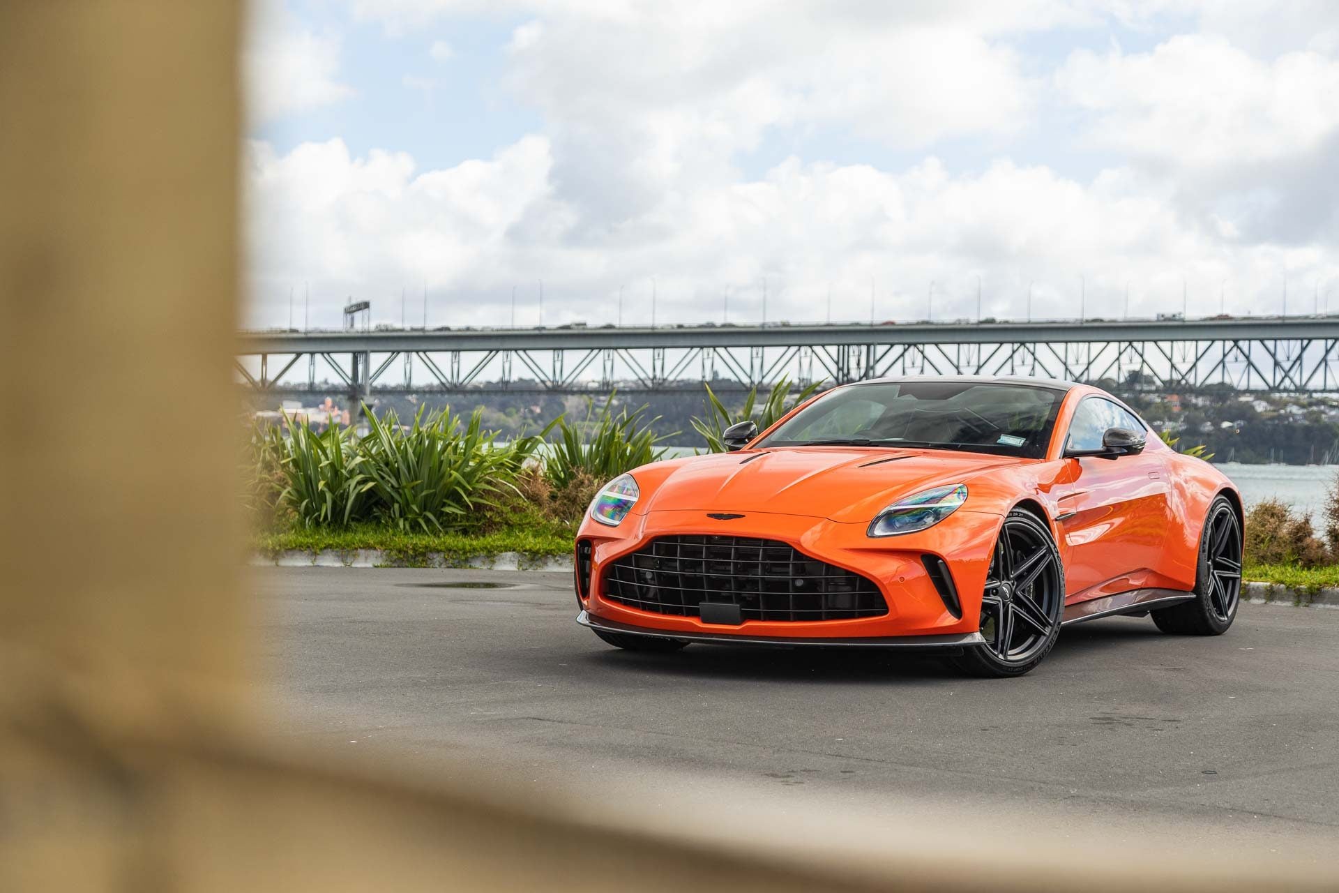 Aaston Martin Vantage 2024, in orange, parked near Auckland's Harbour bridge