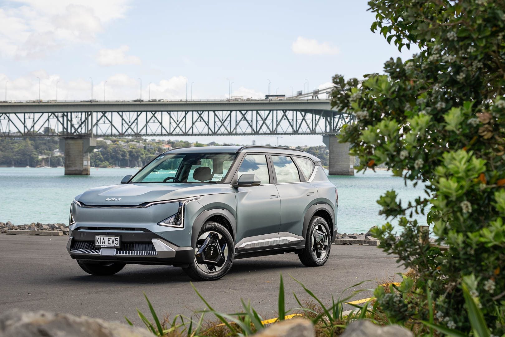 Kia EV5 light+ front quarter shot, with Auckland harbour bridge showing behind
