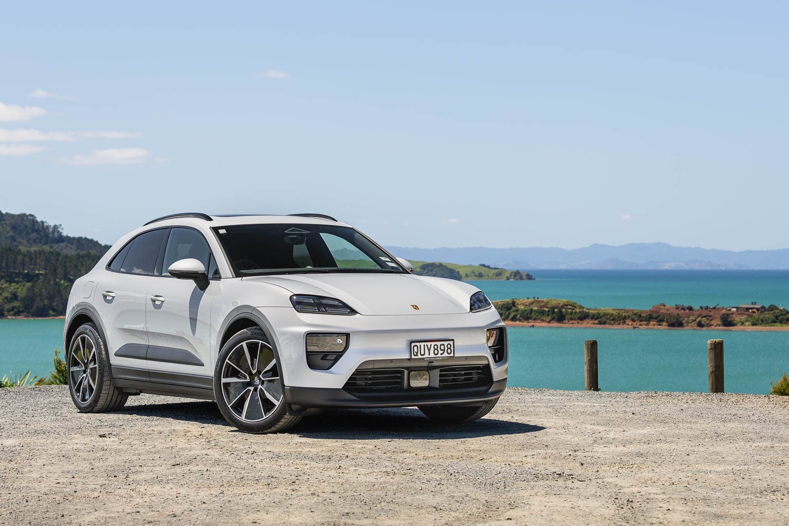 Porsche-Macan 4 EV in white, parked cliffside in front of a harbour