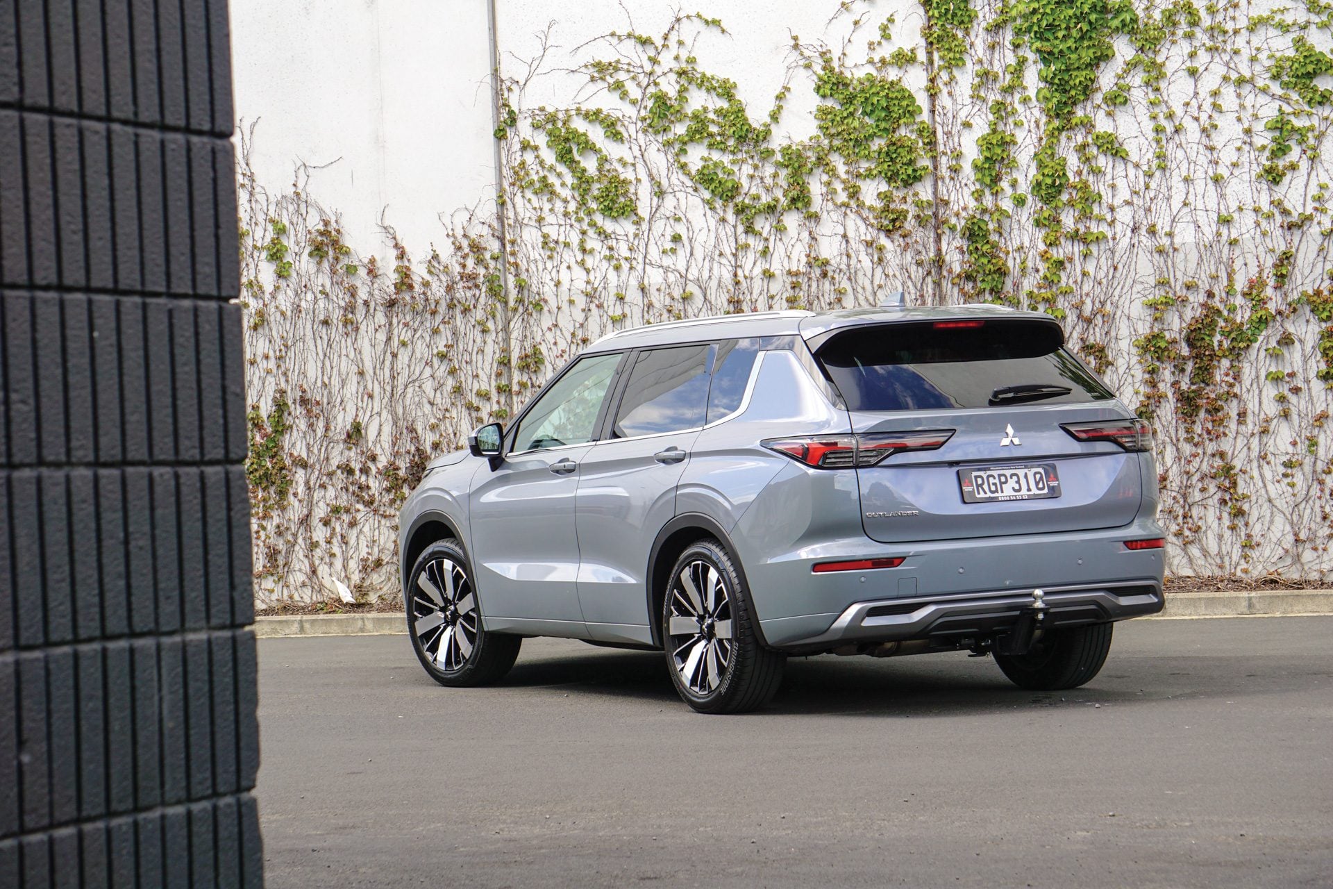 grey outlander parked next to a wall with ivy growing on it