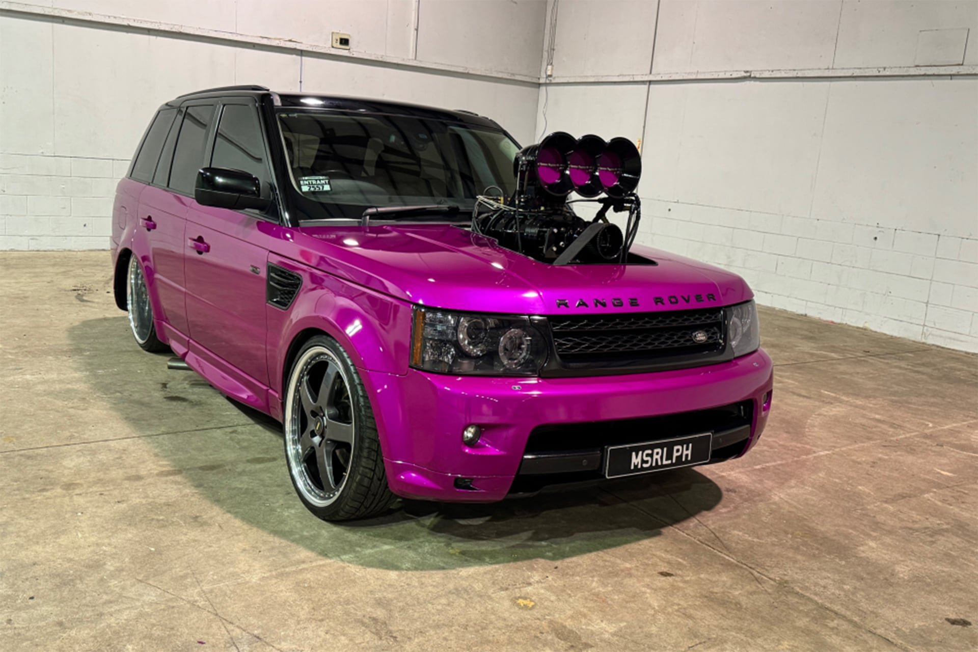 Pink Range Rover on concrete in white warehouse