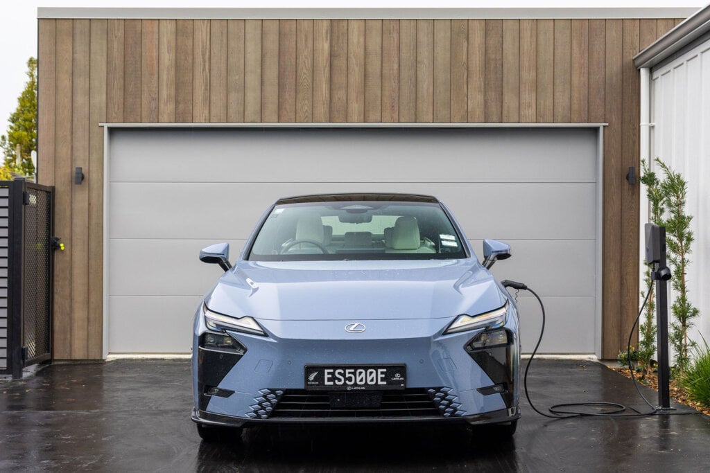Blue Lexus plugged in by a garage