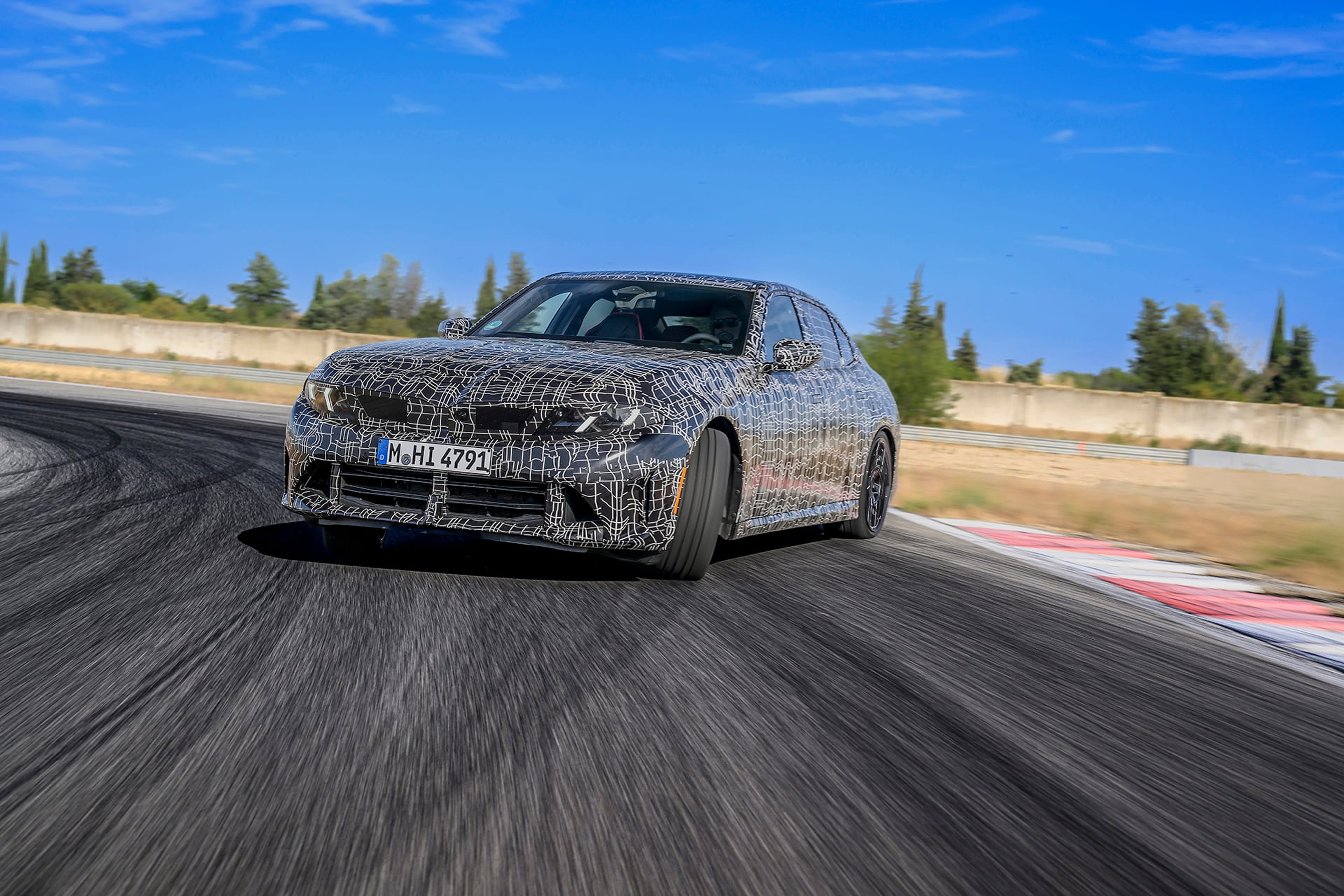 BMW 3 series in camo doing a skid on black tarmac