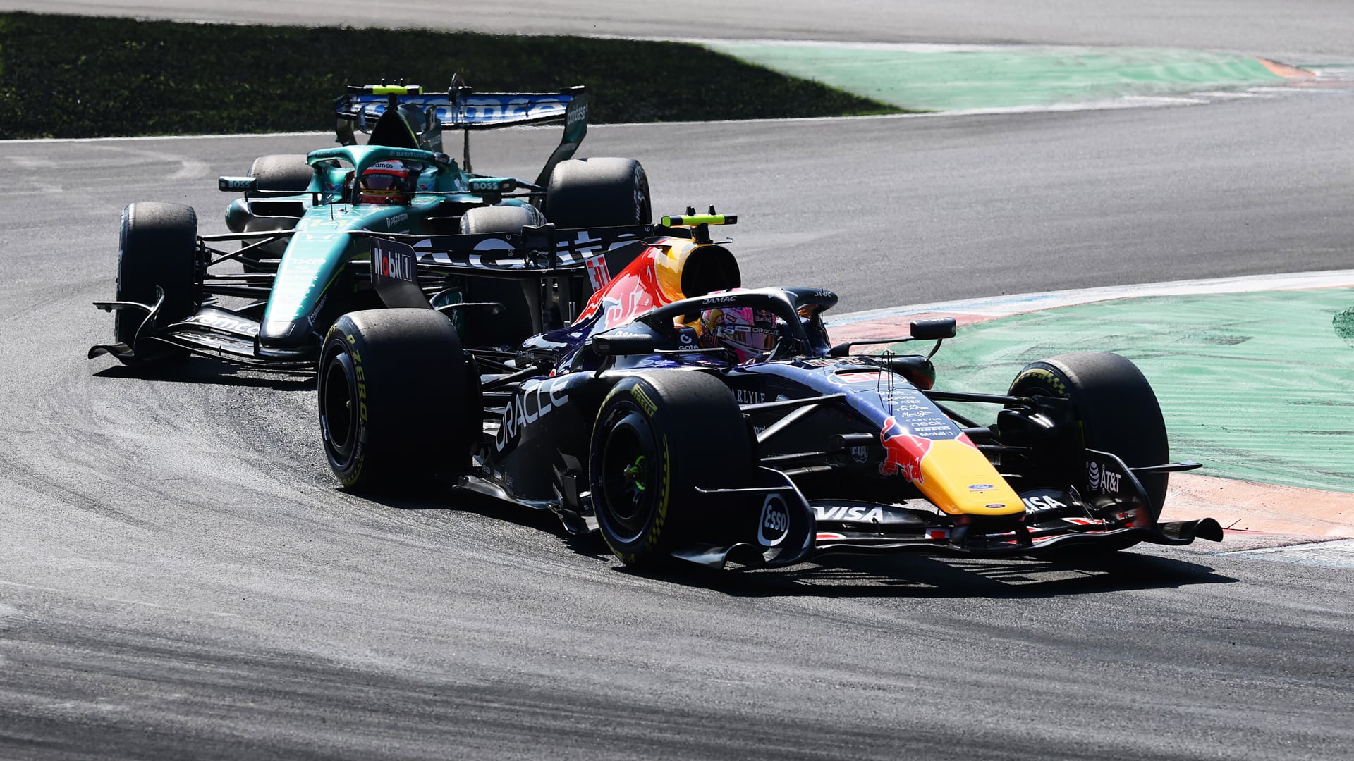 two f1 cars on a track in the sun