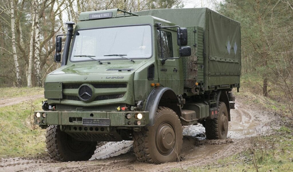 Green Daimler Unimog U 5023 military truck on a muddy forest track
