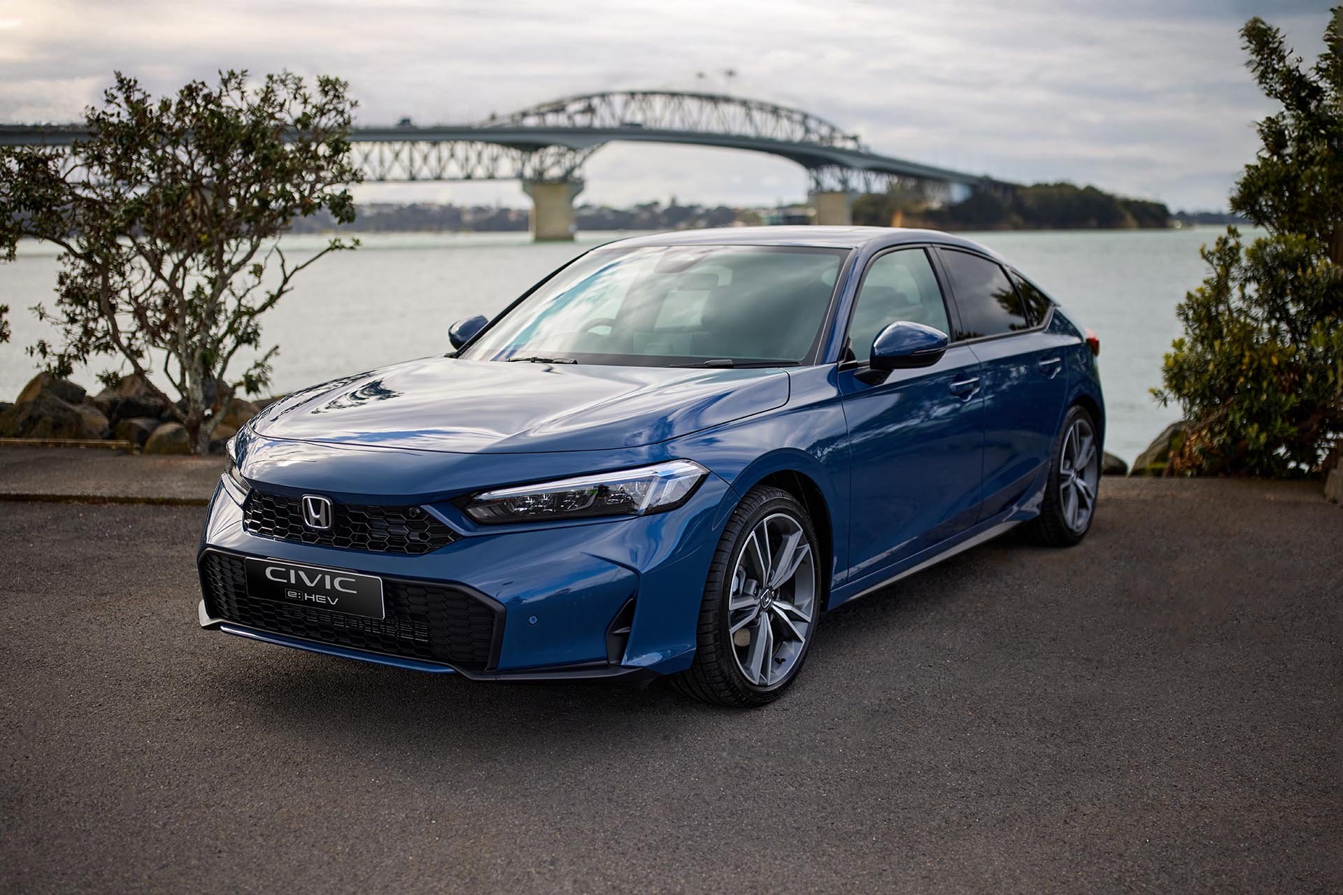 blue honda in front of a bridge