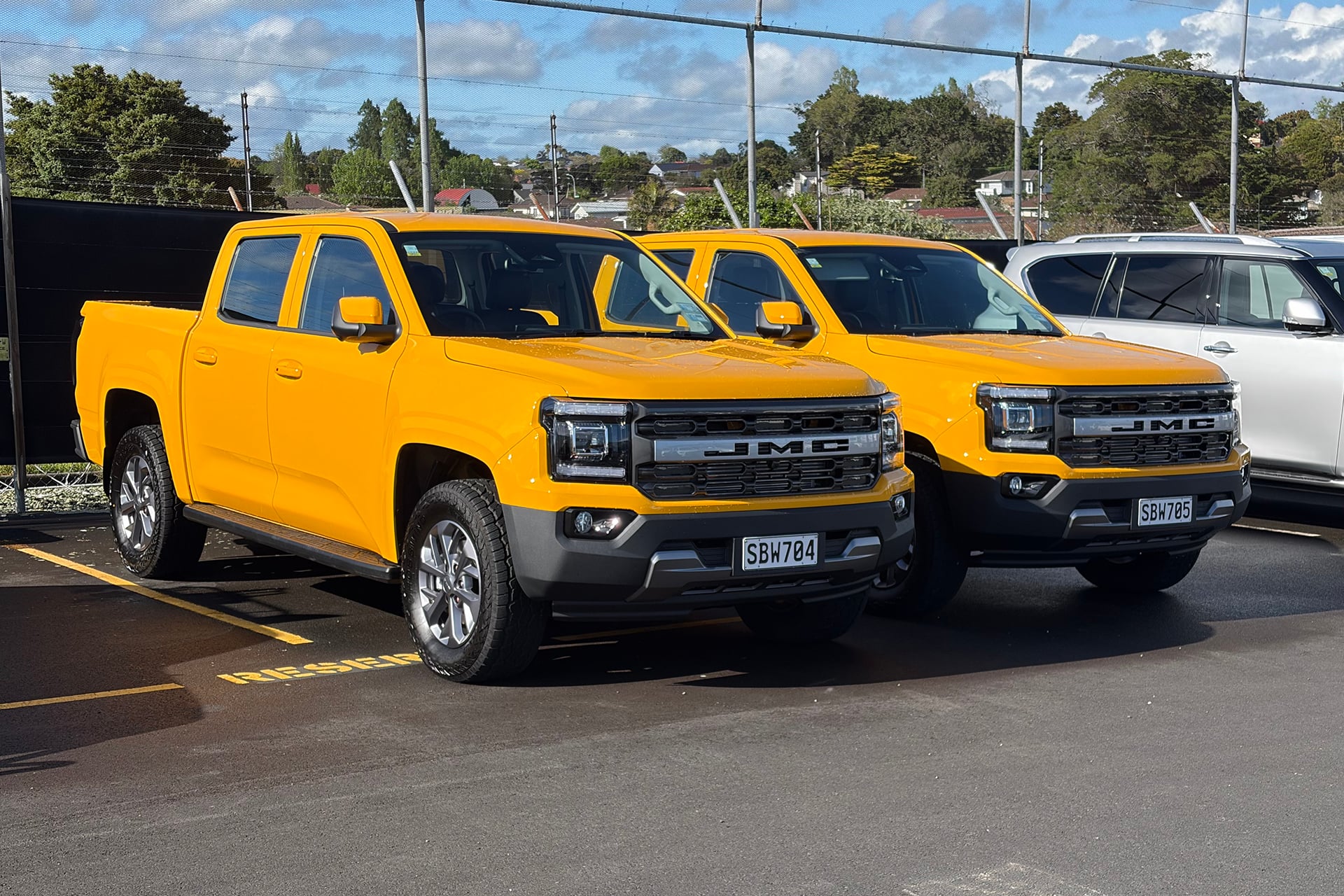 two yellow utes in a carpark