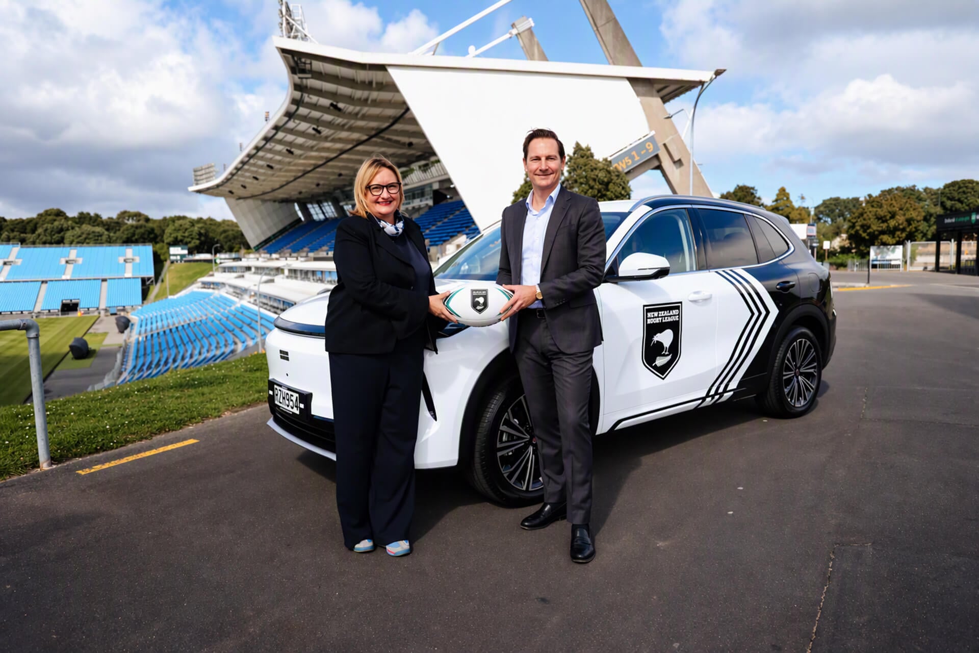 NZRL Geely in white with two people in front of it