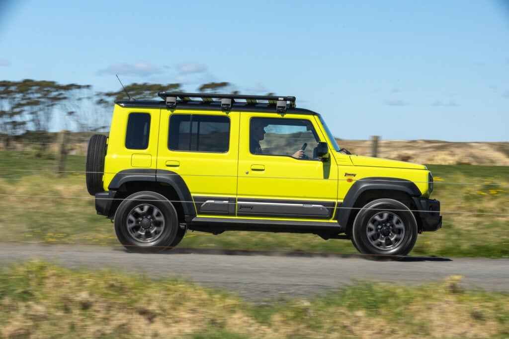 Yellow Suzuki Jimny five-door side view on a rural road