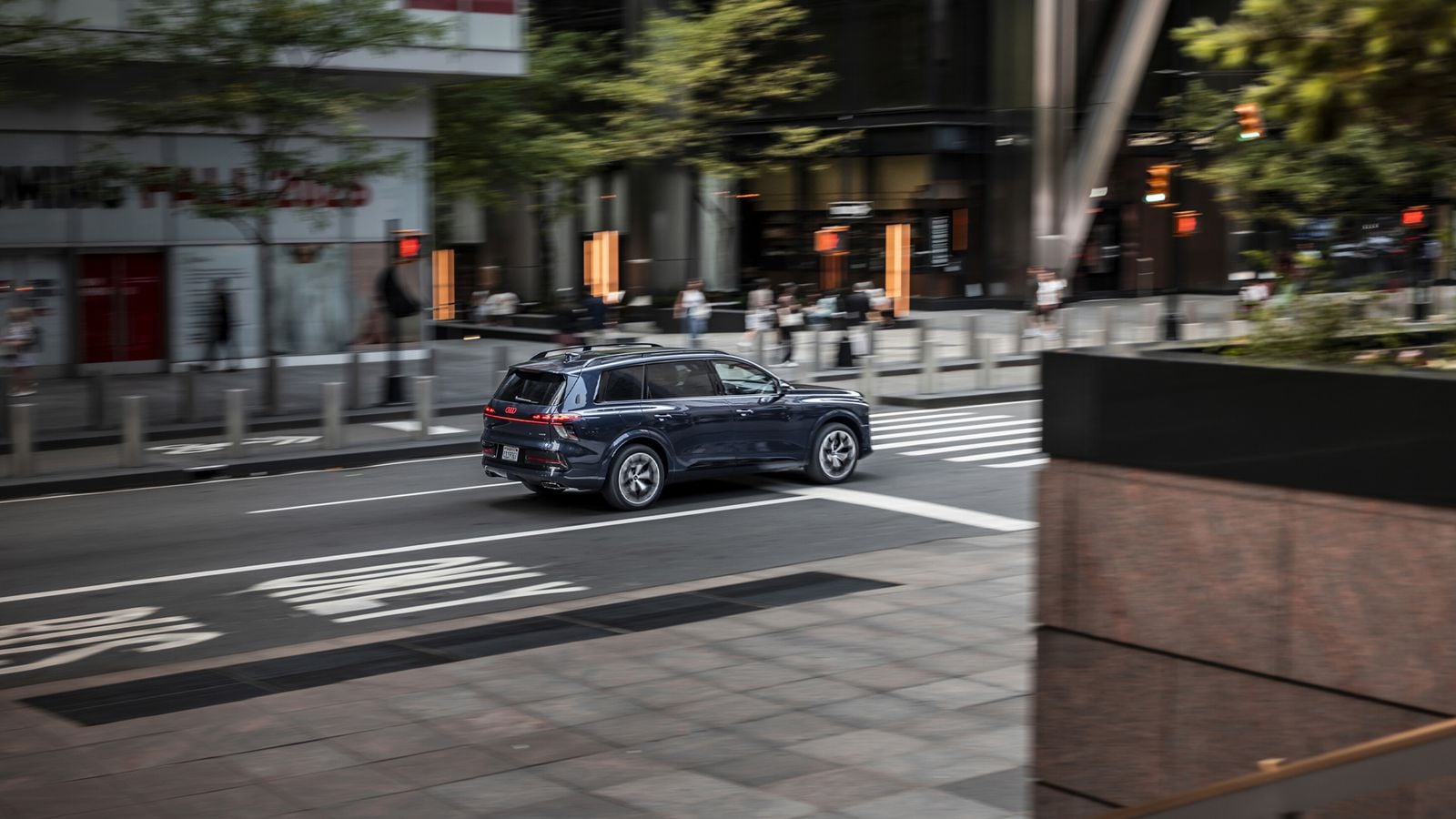 Side profile of the Audi Q9 SUV driving through a city