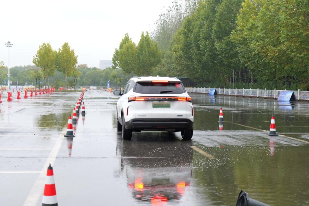 White 2027 Chery Tiggo 4 Hybrid facelift driving through a wet cone course in Wuhu, China