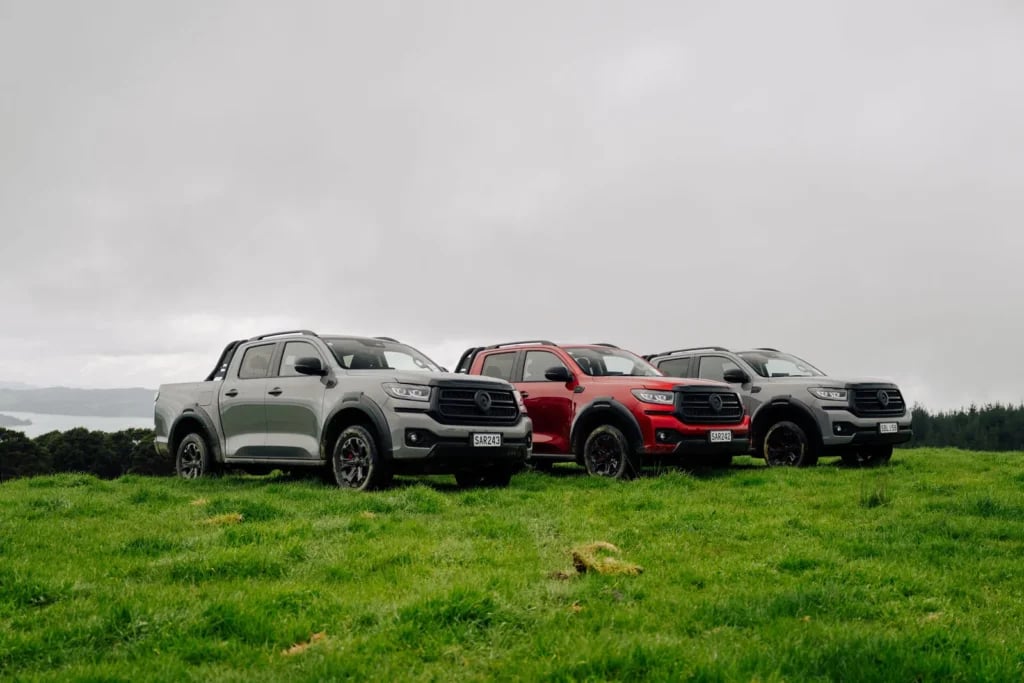 Three GWM Cannon Hi4-T PHEV utes lined up on a hilltop overlooking the coast