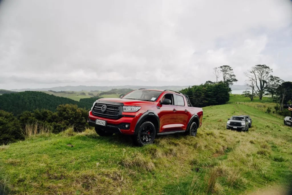 Red GWM Cannon Hi4-T PHEV on a farm hillside
