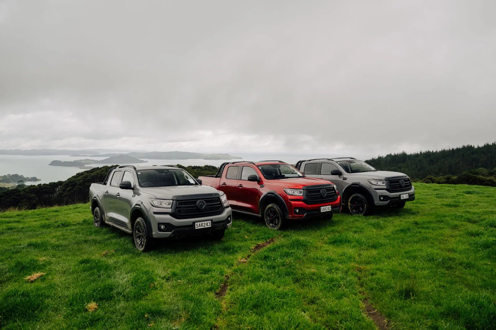 Three GWM Cannon Hi4-T PHEV utes parked on a coastal hilltop