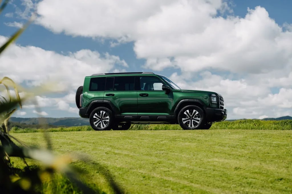 Side profile of the Emerald Green Haval H7 on a grassy hilltop