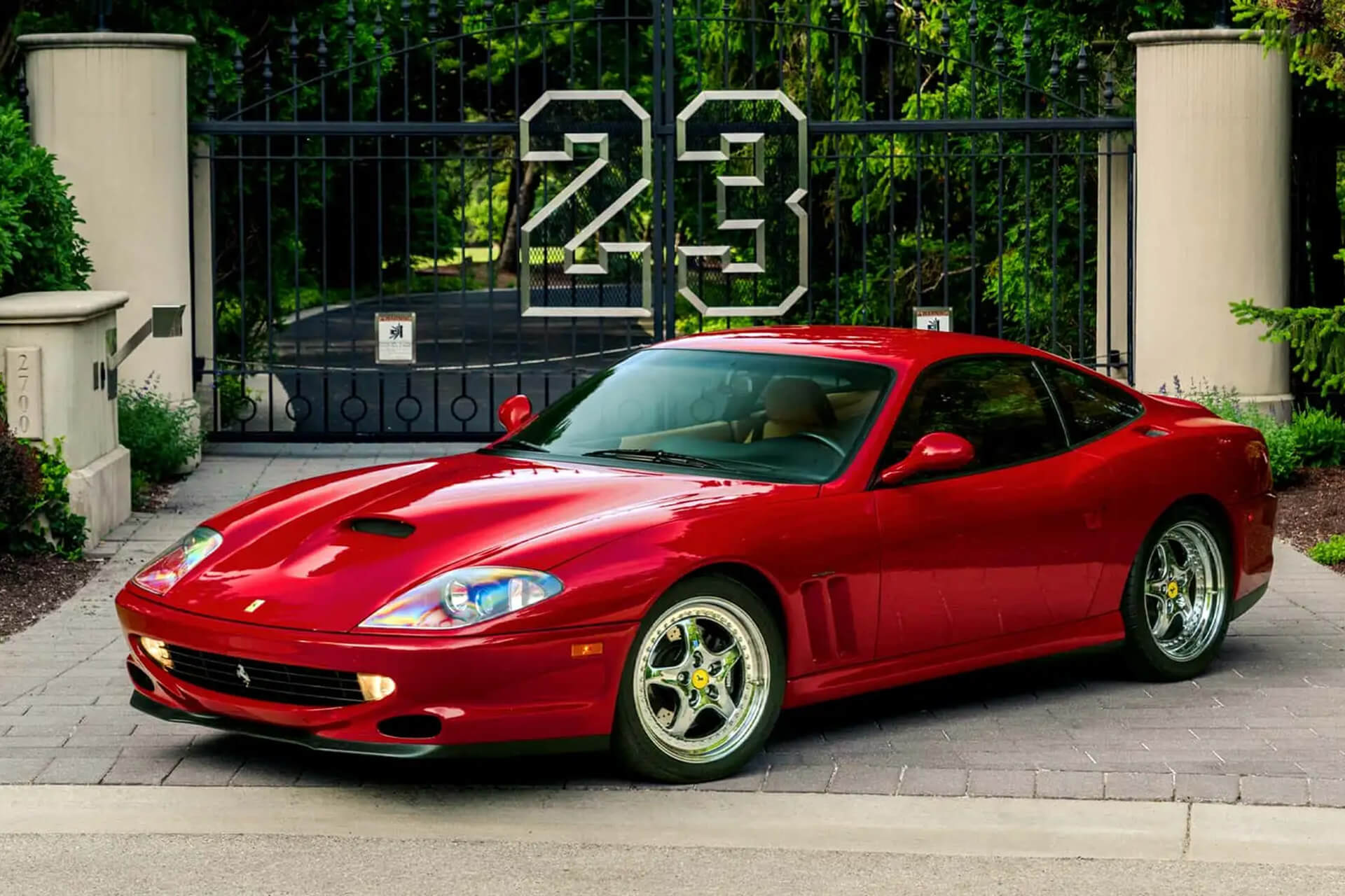 red ferrrari in front of a gate and the number 23