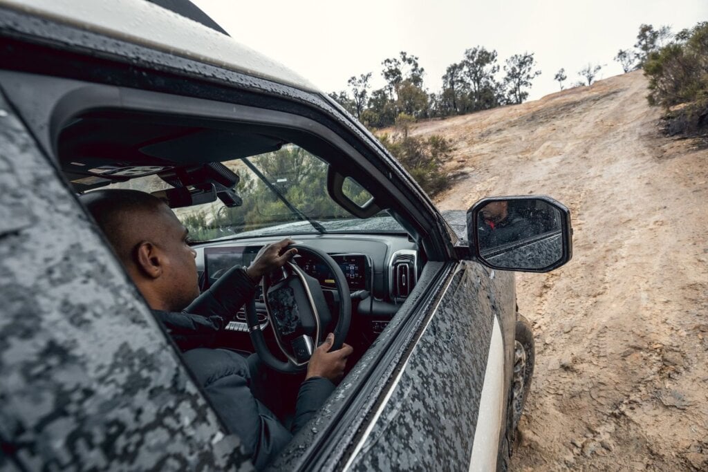 Camouflaged Nissan Navara Pro PHEV prototype climbing a dirt track during testing in Australia