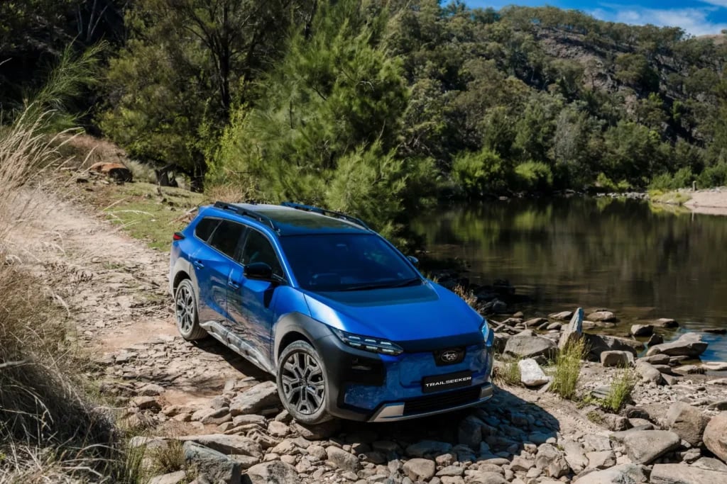 Blue Subaru Trailseeker AWD Touring on a rocky track beside a river
