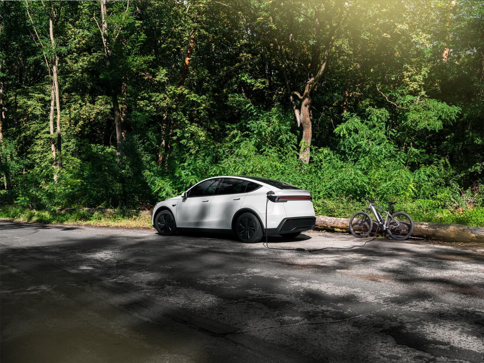 White Tesla Model Y powering an e-bike charger