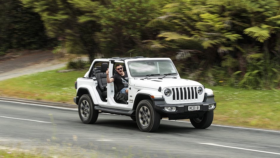 2019 Jeep Wrangler Overland Unlimited driving on road with doors and roof removed