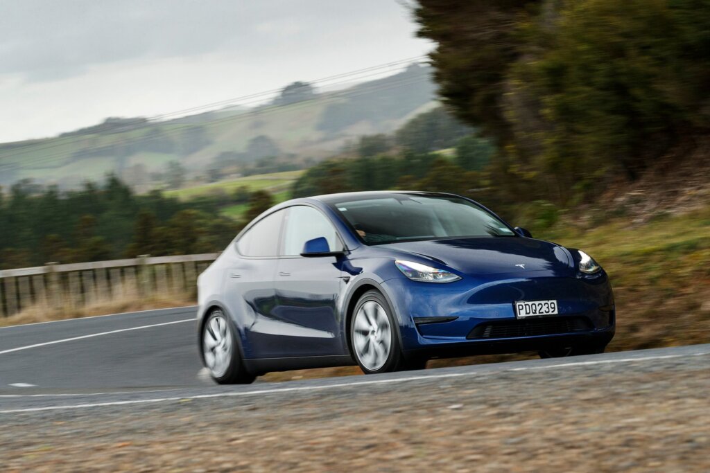 Tesla Model Y front three quarter view driving on road