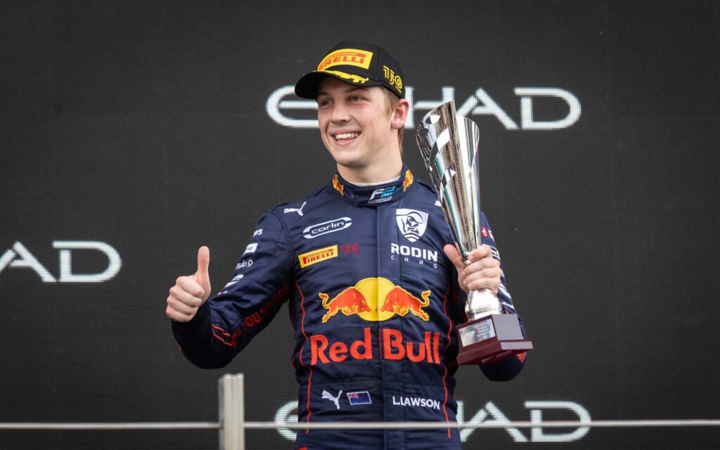 Liam Lawson holding up trophy on podium