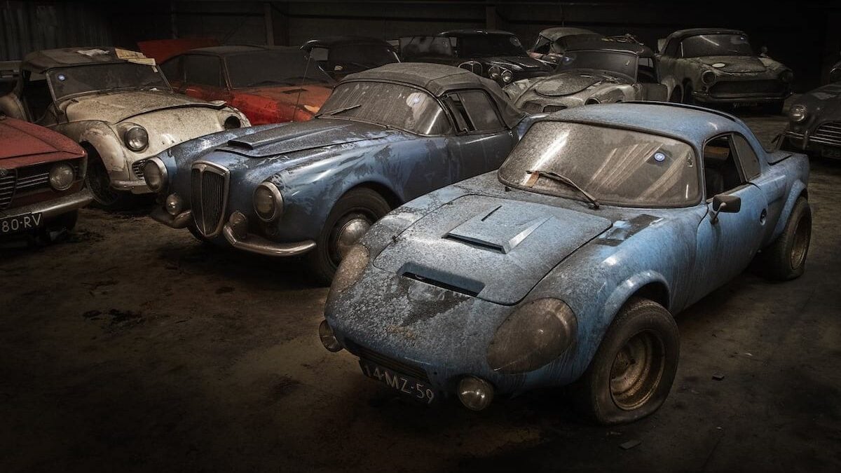Old cars covered in dust parked in warehouse