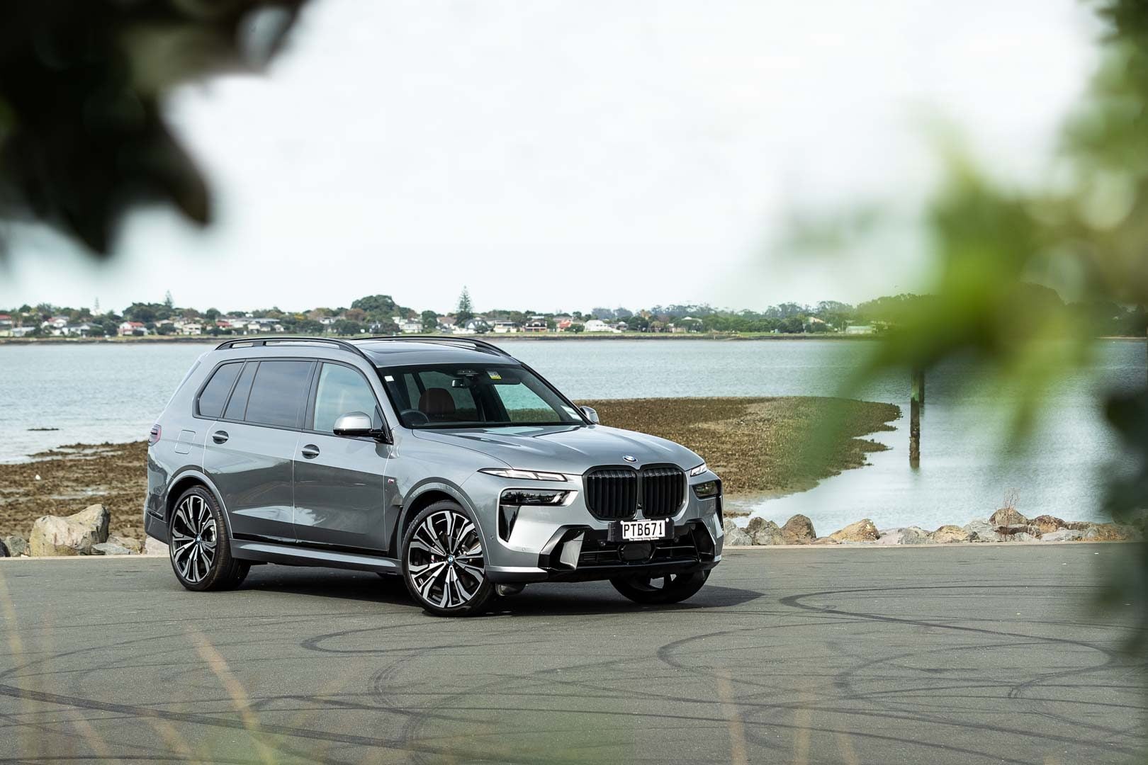 BMW X7 xDrive40D front quarter shot behind leaves