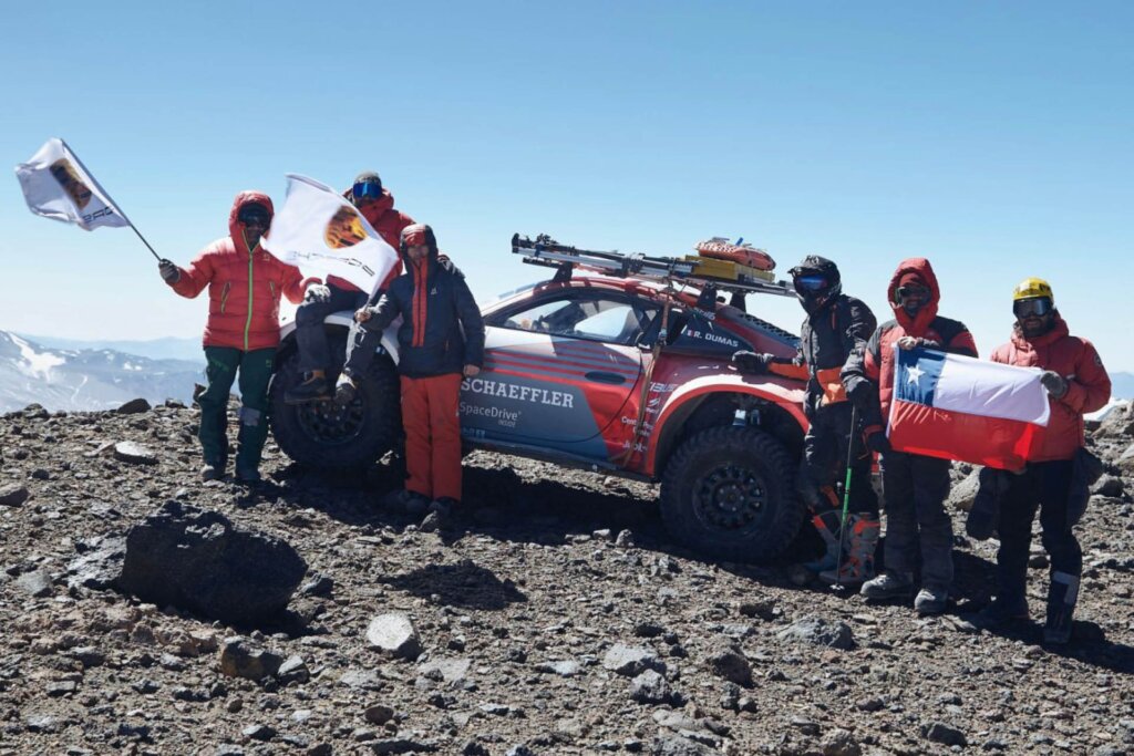 Team of people celebrate driving Porsche 911 up the world's tallest volcano