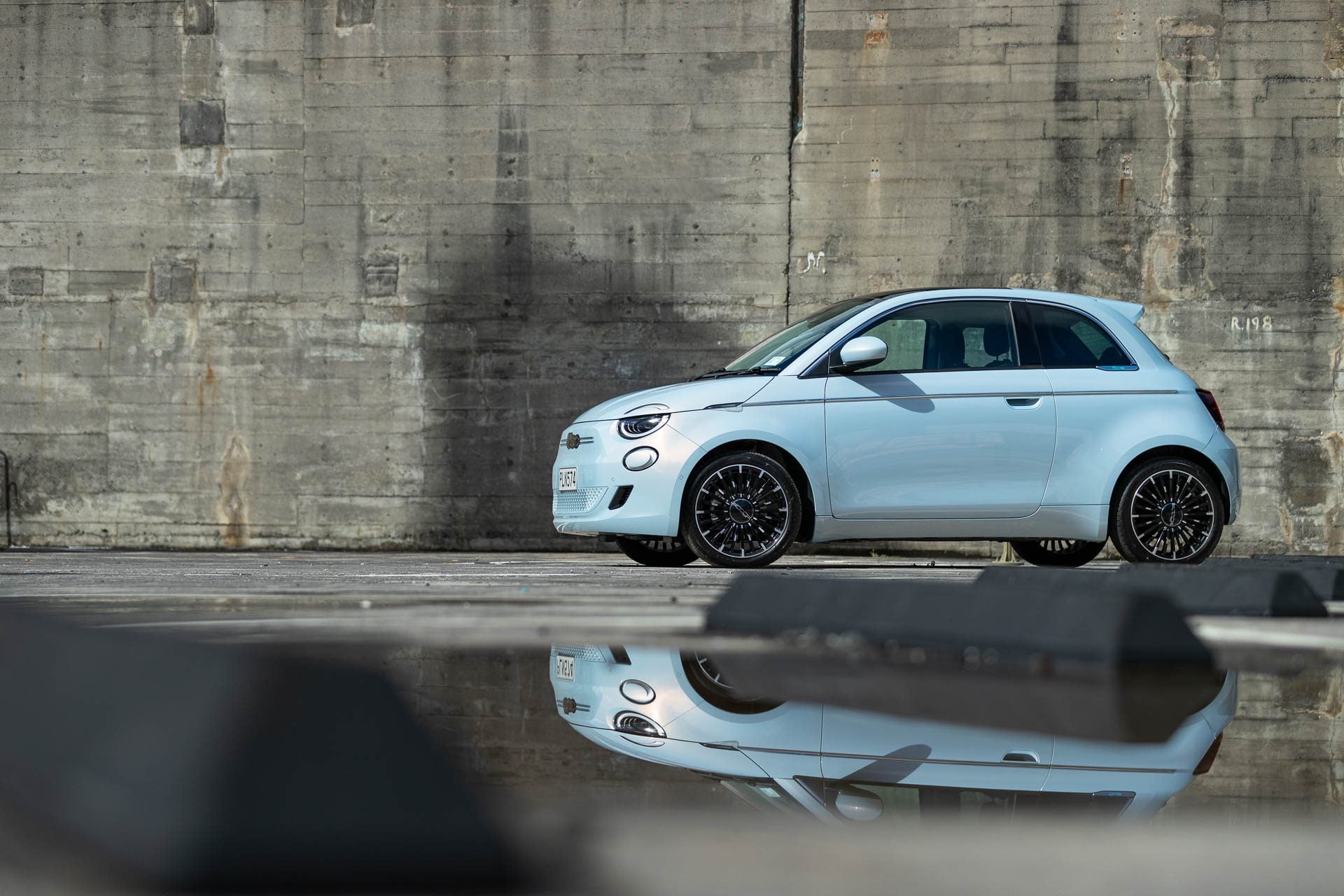Fiat 500 in city scene reflected in puddle.