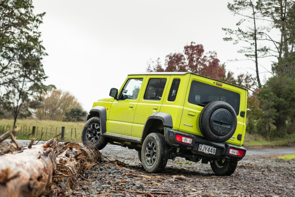 Suzuki Jimny 5-Door flexing, parked on top of a log