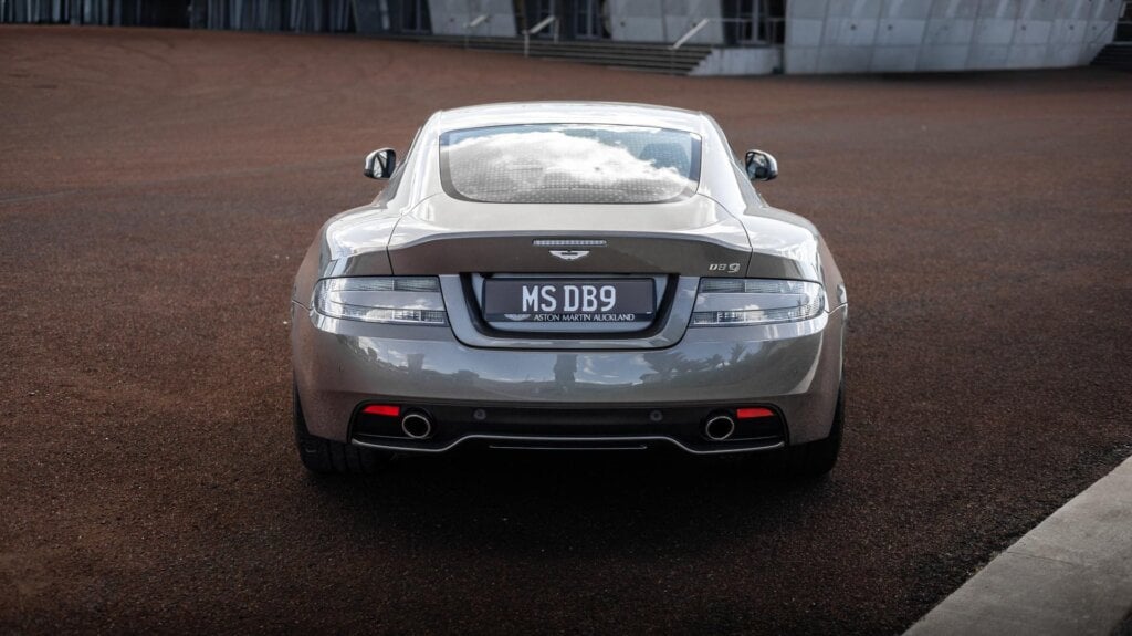 Aston Martin DB9 in silver, parked on red concrete