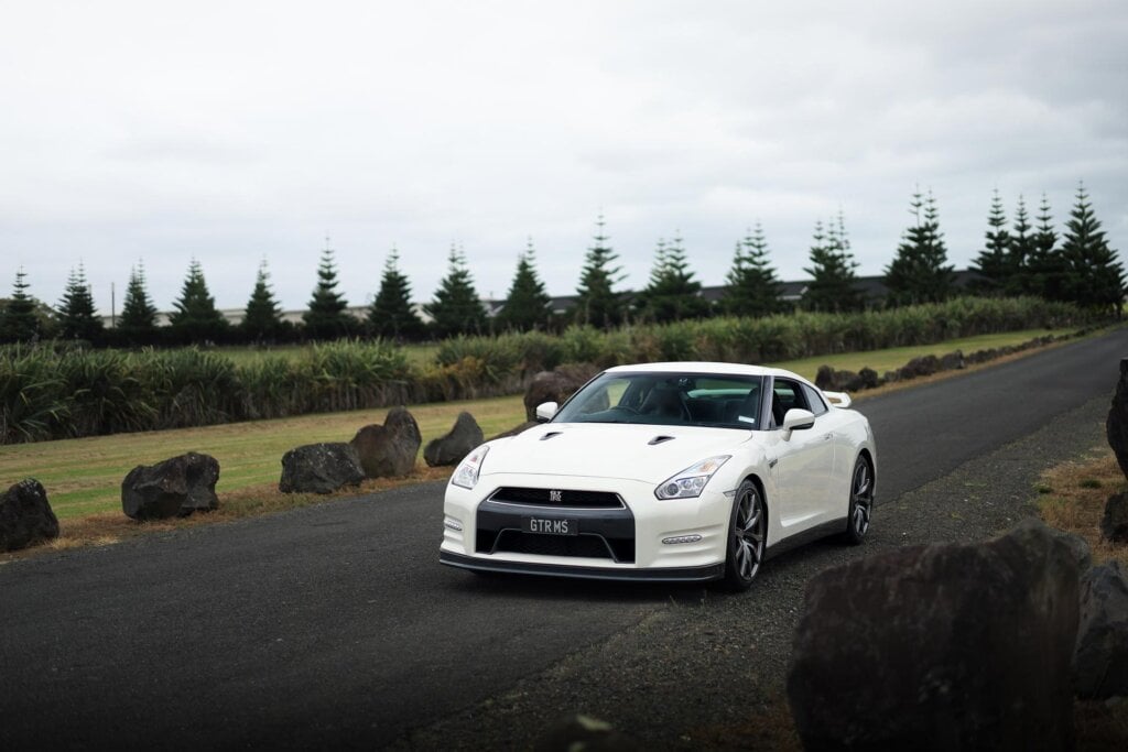 Nissan GT-R R35 in white, parked on a quiet road near rocks