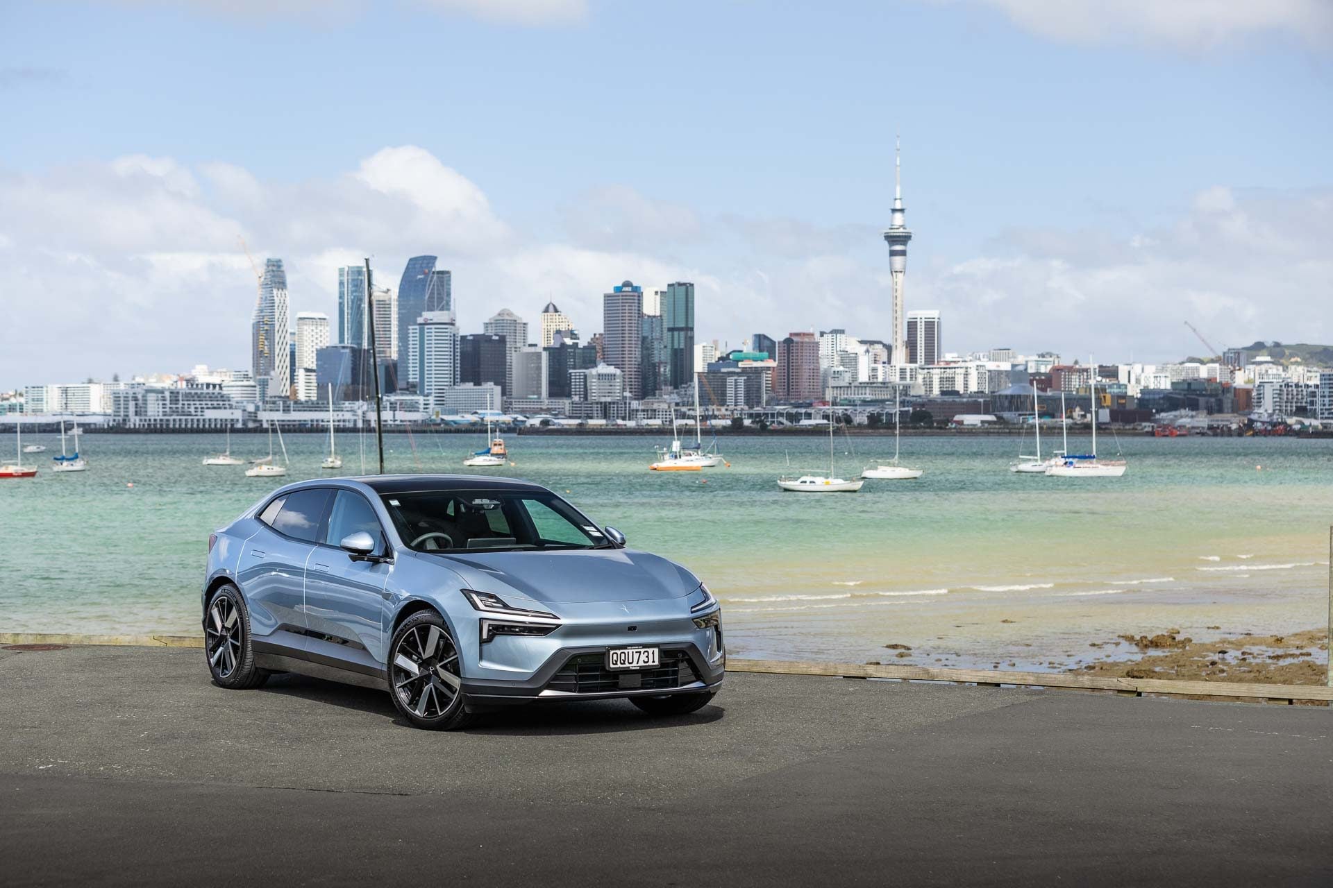 Polestar 4 Long Range dual motor, parked in front of Auckland's city scape