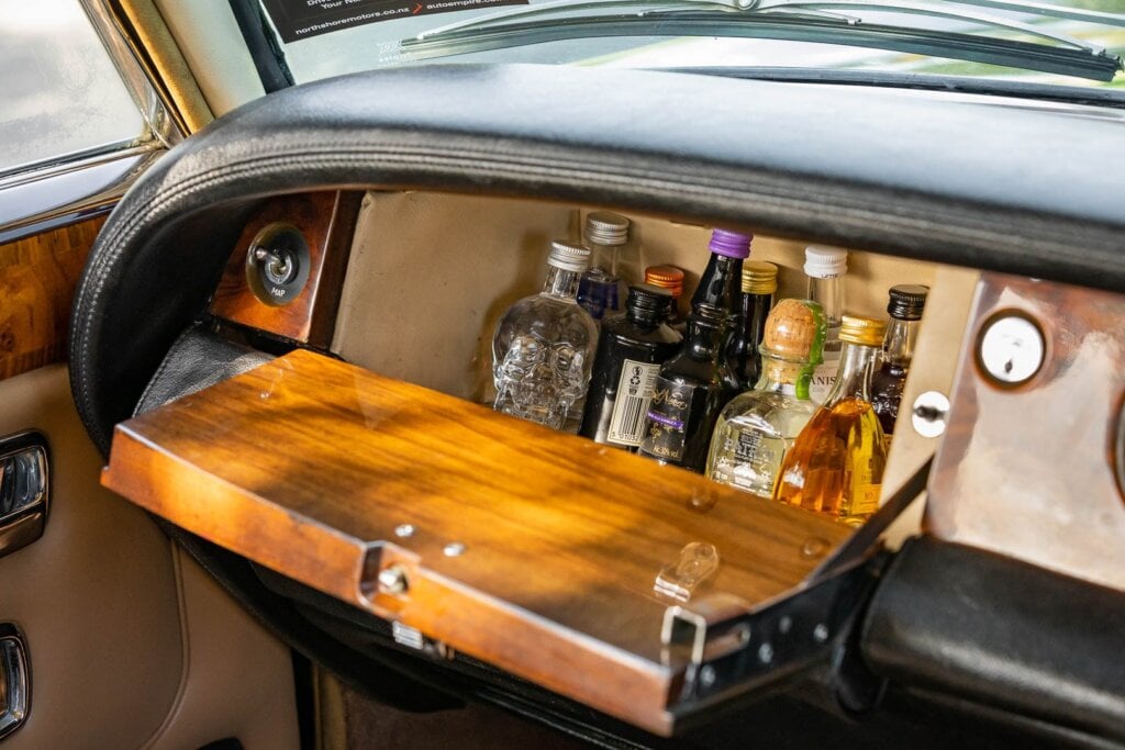 Liquor stash inside the Rolls, with a map light switch, and wooden glovebox door