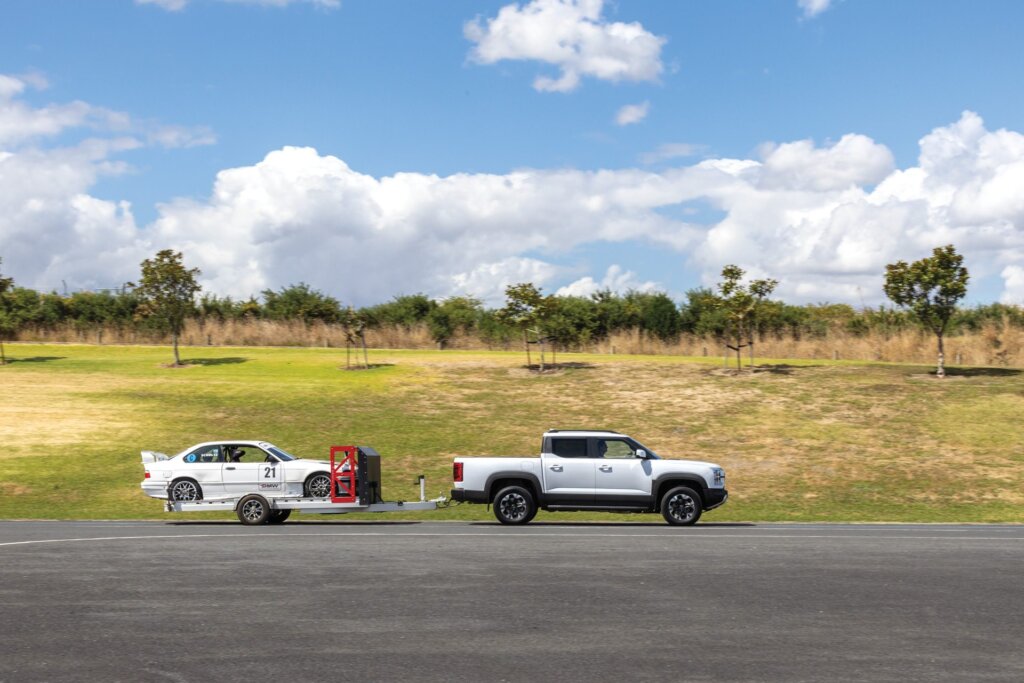 BYD Shark 6 in action towing a race car.