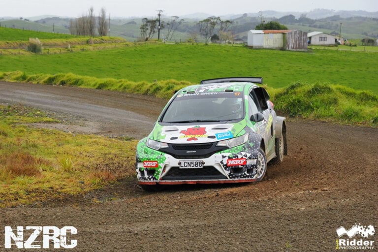 white and green rally car on gravel road
