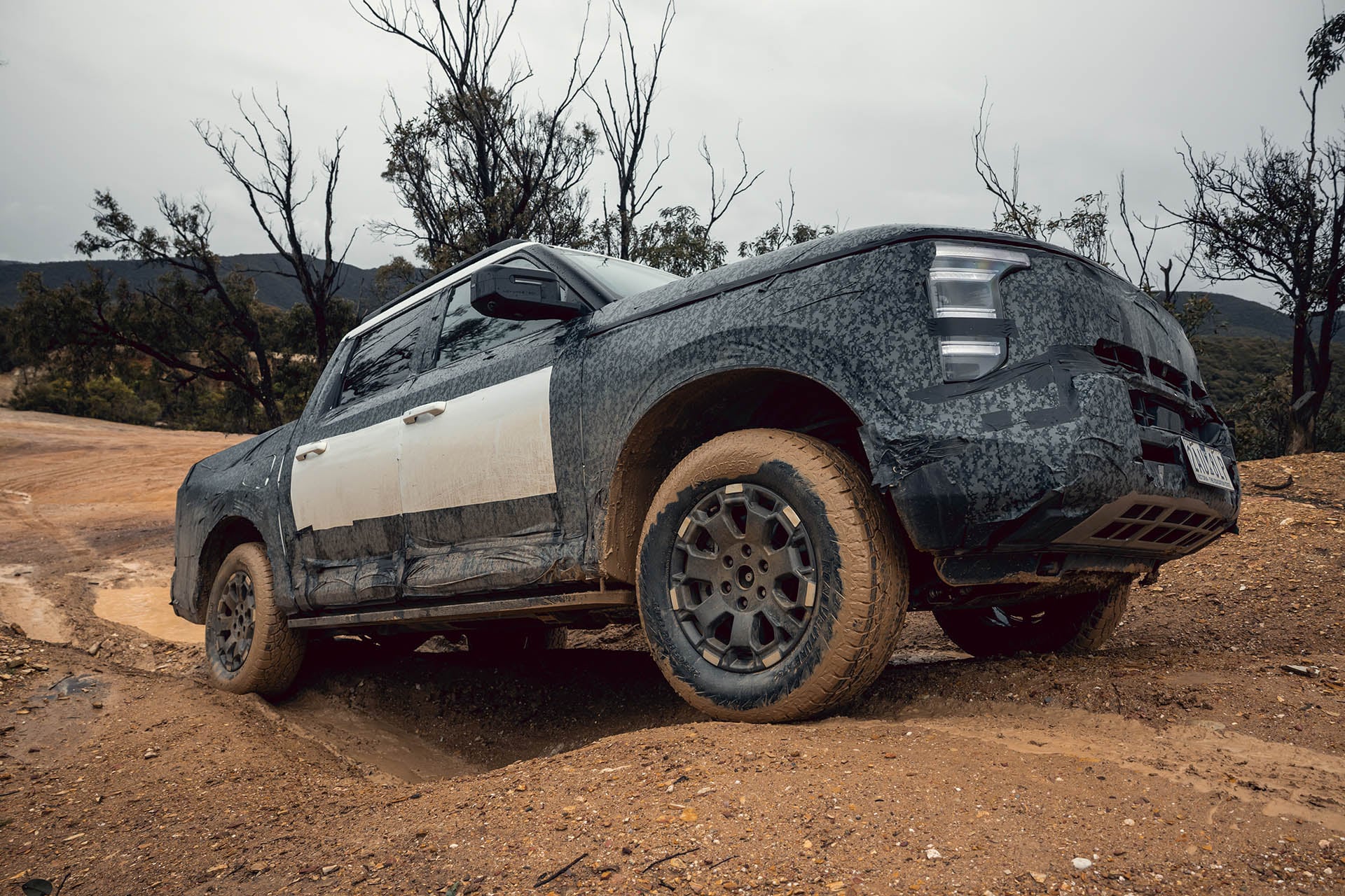 A Nissan ute covered in black cladding getting muddy