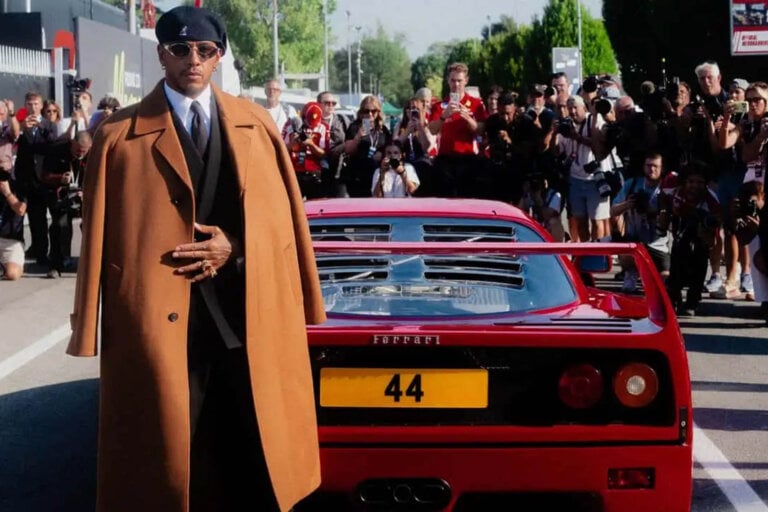 Lewis Hamilton in a brown coat next to a red F40
